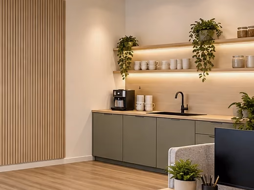 Visualisierung: Küchenzeile mit Kaffeemaschine, Spüle und Regalen mit Tassen, davor ein Sessel der Lounge